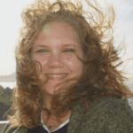 Lee-Anne, owner of Sea Sprite, in green sweater smiling as hair blows in wind