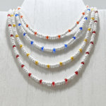 Paradise Orange displayed with multiple white seed bead choker necklace with red, orange, blue, and yellow accent beads