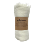 The Boho Shawl White rolled up with Rubyzaar packaging of brown paper with product name and description written in black. Displayed on white background.